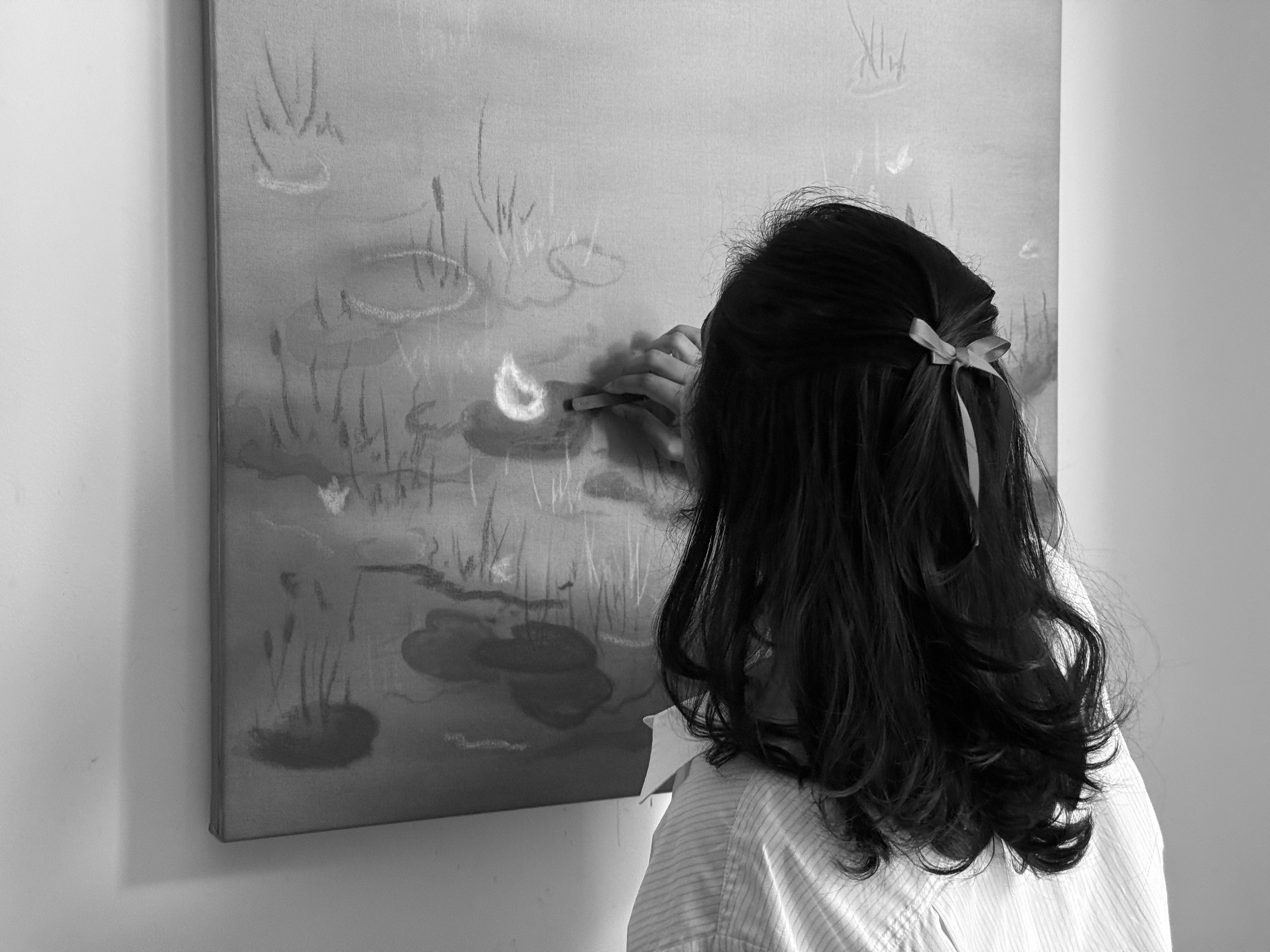 Person looking at a painting of a lily pond with reeds.